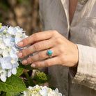 [KI] Silberring mit Türkis an der Hand zwischen Blumen