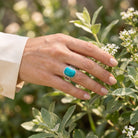 [KI] Silberring mit Türkis an der Hand zwischen Blumen