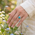 [KI] Silberring mit Türkis an der Hand zwischen Blumen