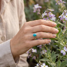 [KI] Silberring mit Türkis an der Hand zwischen Blumen