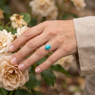 [KI] Silberring mit Türkis an der Hand zwischen Blumen