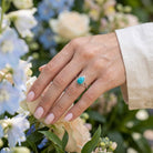 [KI] Silberring mit Türkis an der Hand zwischen Blumen