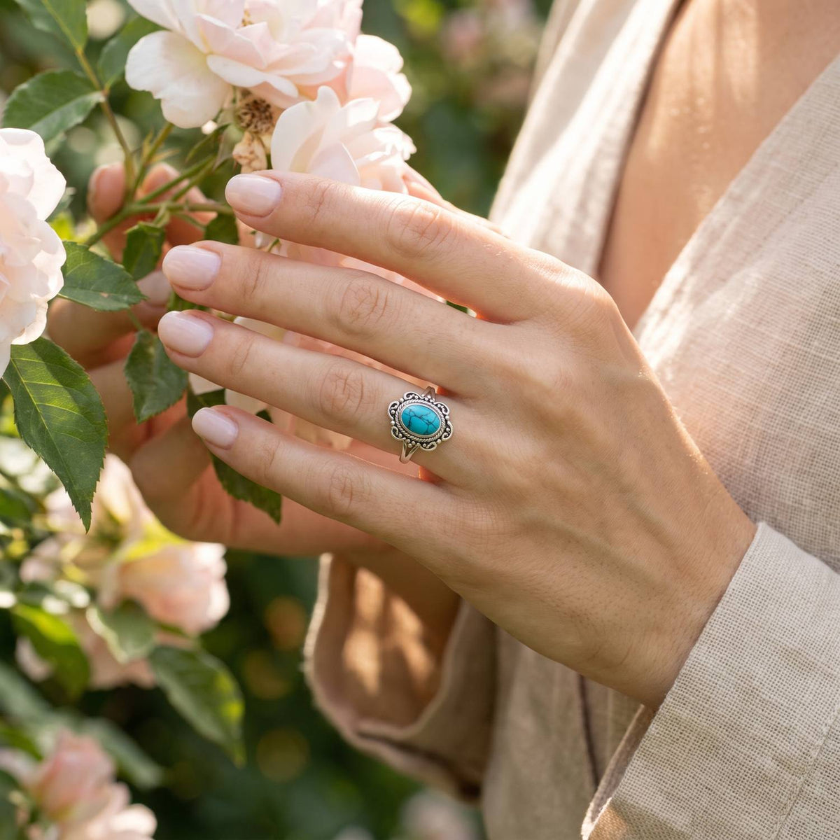 Silberring mit Türkis an der Hand zwischen Blumen