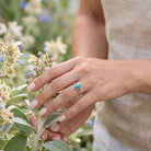 [KI] Silberring mit Türkis an der Hand zwischen Blumen