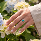 [KI] Silberring mit Türkis an der Hand zwischen Blumen