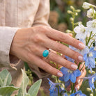 [KI] Silberring mit Türkis an der Hand zwischen Blumen