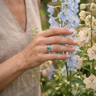 [KI] Silberring mit Türkis an der Hand zwischen Blumen