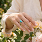 [KI] Silberring mit Türkis an der Hand zwischen Blumen