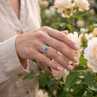 [KI] Silberring mit Türkis an der Hand zwischen Blumen