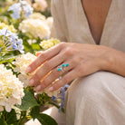 [KI] Silberring mit Türkis an der Hand zwischen Blumen