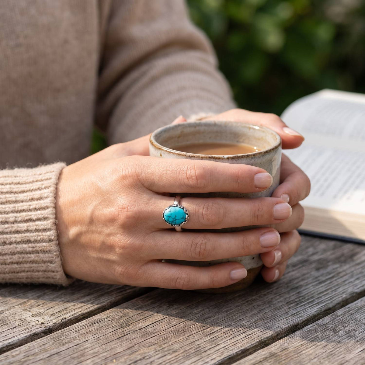 Türkisring aus Silber getragen beim Lesen mit einer Tasse