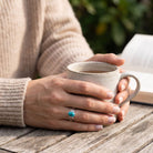 [KI] Türkisring aus Silber getragen beim Lesen mit einer Tasse