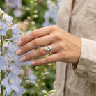 [KI] Silberring mit Topas an der Hand zwischen Blumen