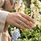 [KI] Silberring mit Topas an der Hand zwischen Blumen