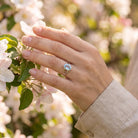 [KI] Silberring mit Topas an der Hand zwischen Blumen