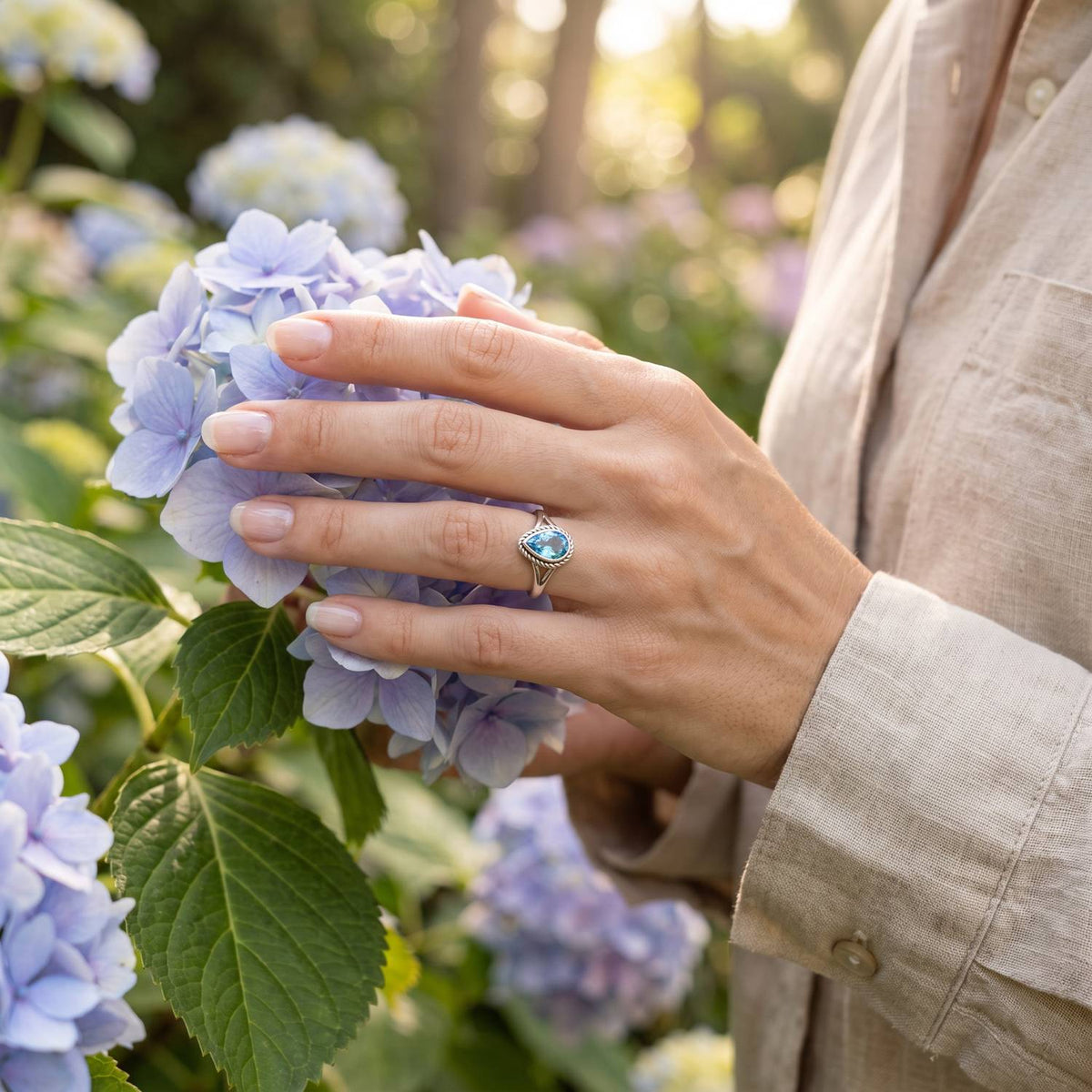 Silberring mit Topas an der Hand zwischen Blumen