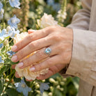 [KI] Silberring mit Topas an der Hand zwischen Blumen
