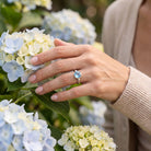 [KI] Silberring mit Topas an der Hand zwischen Blumen