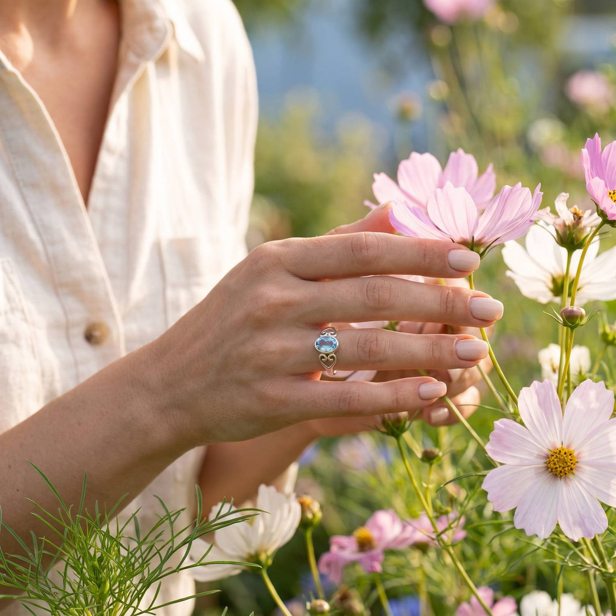 Silberring mit Topas an der Hand zwischen Blumen