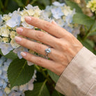 [KI] Silberring mit Topas an der Hand zwischen Blumen