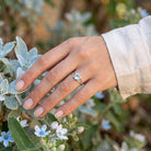 [KI] Silberring mit Topas an der Hand zwischen Blumen