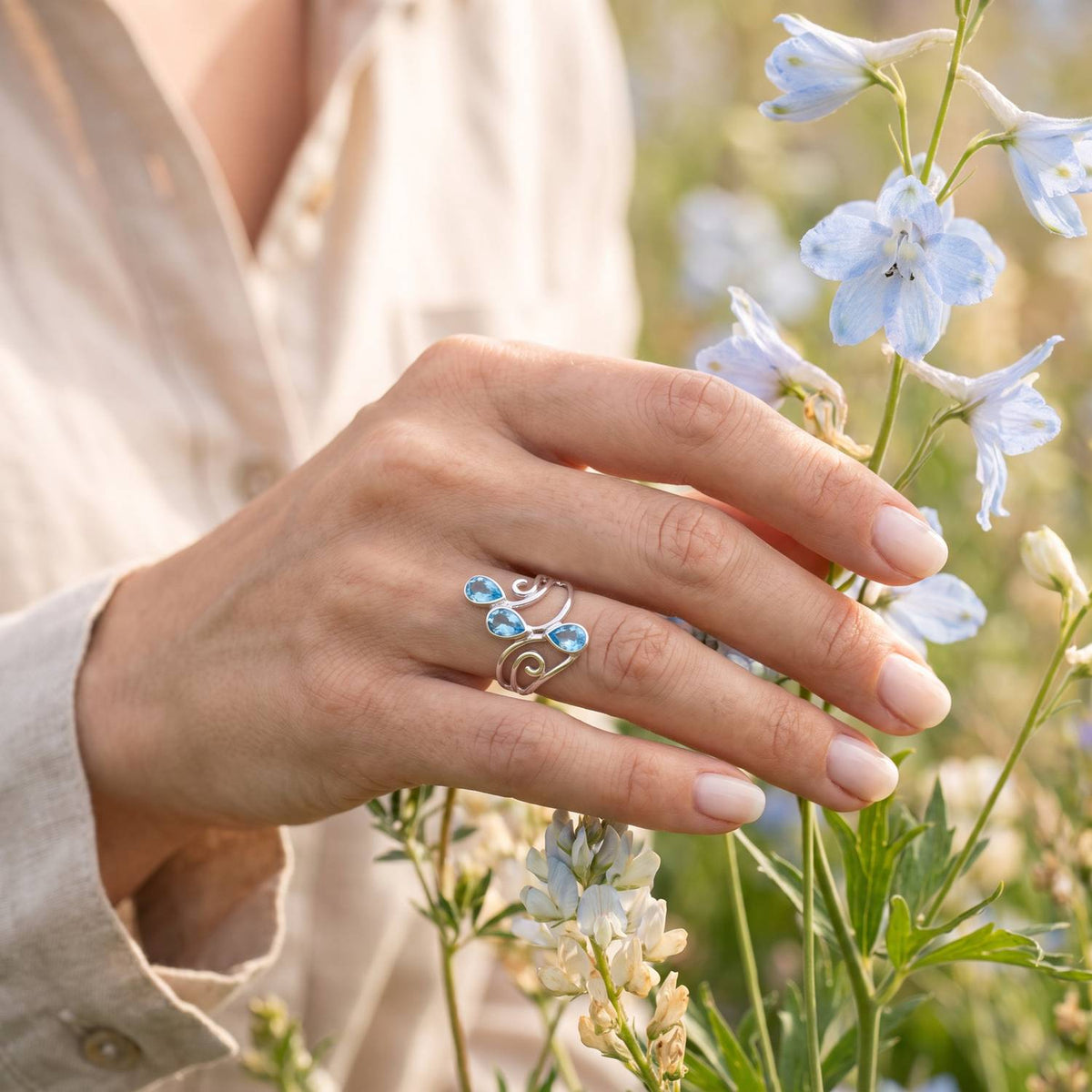 Silberring mit Topas an der Hand zwischen Blumen