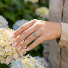 [KI] Silberring mit Topas an der Hand zwischen Blumen