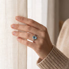 [KI] Frau trägt einen Topasring aus Silber am Fenster
