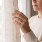 [KI] Frau trägt einen Topasring aus Silber am Fenster