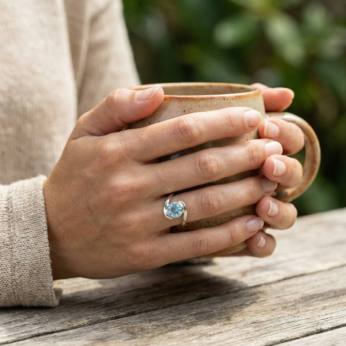 Topasring aus Silber getragen beim Lesen mit einer Tasse