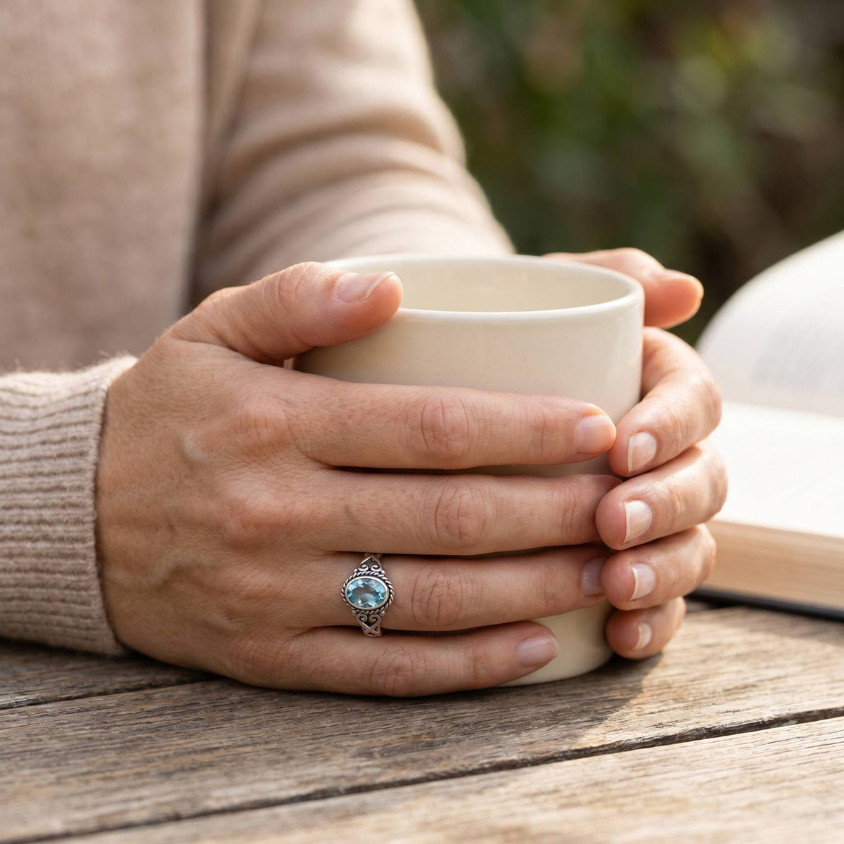 Topasring aus Silber getragen beim Lesen mit einer Tasse