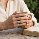 [KI] Topasring aus Silber getragen beim Lesen mit einer Tasse