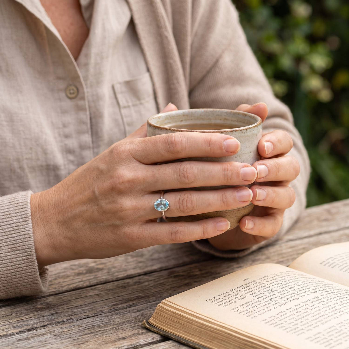 Topasring aus Silber getragen beim Lesen mit einer Tasse