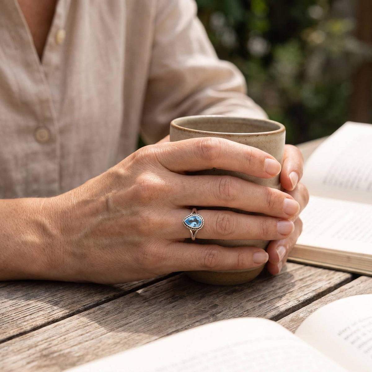Topasring aus Silber getragen beim Lesen mit einer Tasse