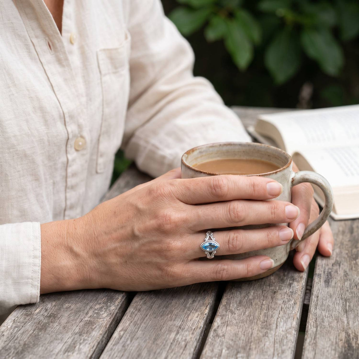 Topasring aus Silber getragen beim Lesen mit einer Tasse