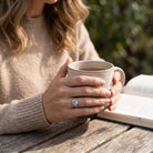 [KI] Topasring aus Silber getragen beim Lesen mit einer Tasse
