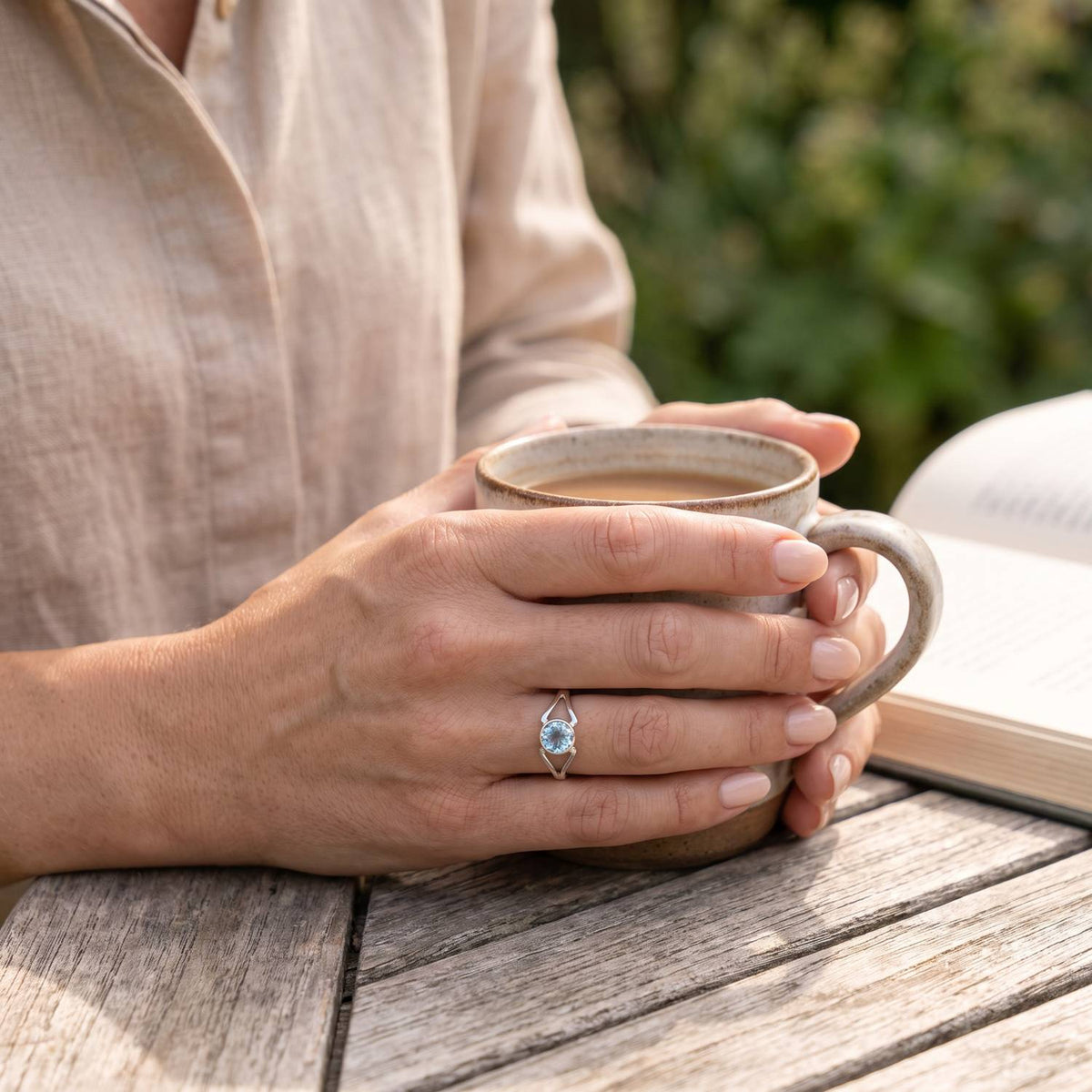 Topasring aus Silber getragen beim Lesen mit einer Tasse