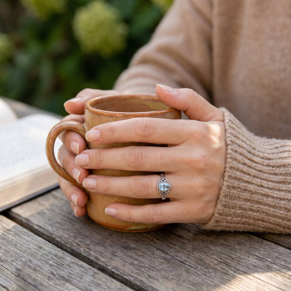 Topasring aus Silber getragen beim Lesen mit einer Tasse