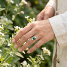[KI] Silberring mit grüner Onyx an der Hand zwischen Blumen