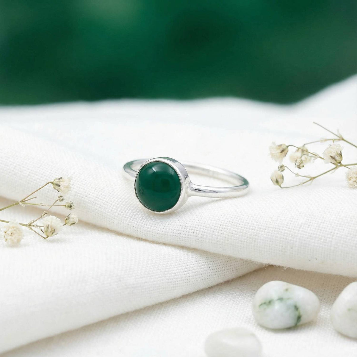 Silberring mit grüner Onyx auf hellem Stoff