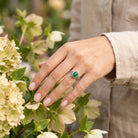 [KI] Silberring mit grüner Onyx an der Hand zwischen Blumen