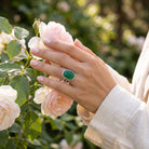 [KI] Silberring mit grüner Onyx an der Hand zwischen Blumen
