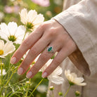 [KI] Silberring mit grüner Onyx an der Hand zwischen Blumen