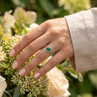 [KI] Silberring mit grüner Onyx an der Hand zwischen Blumen