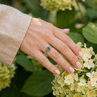 [KI] Silberring mit grüner Onyx an der Hand zwischen Blumen
