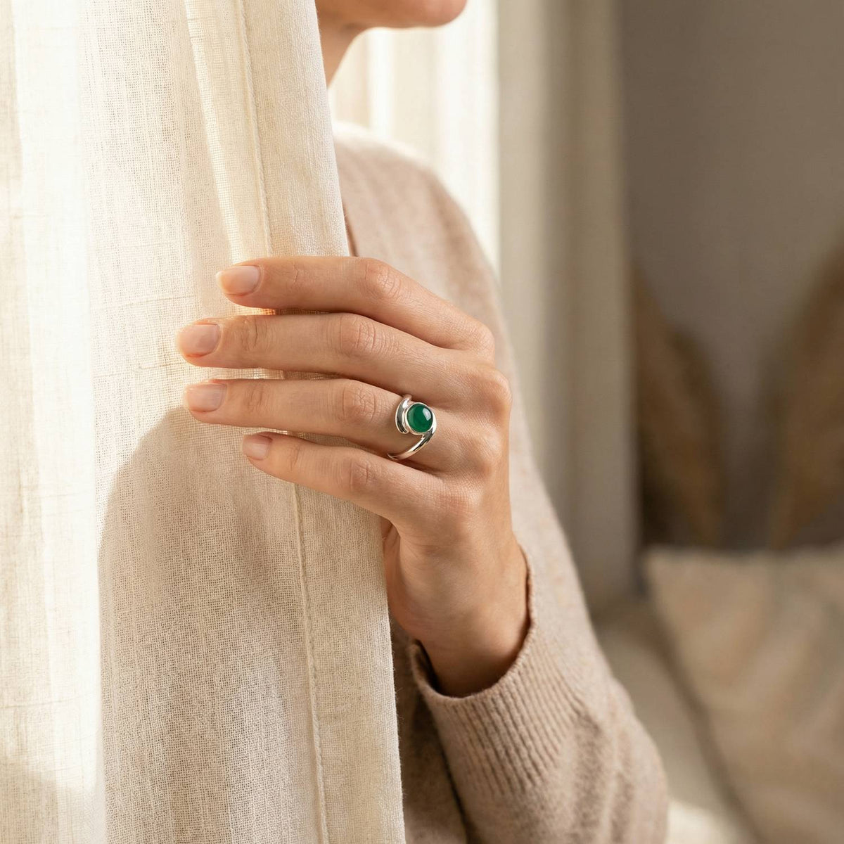 Frau trägt einen grüner Onyxring aus Silber am Fenster