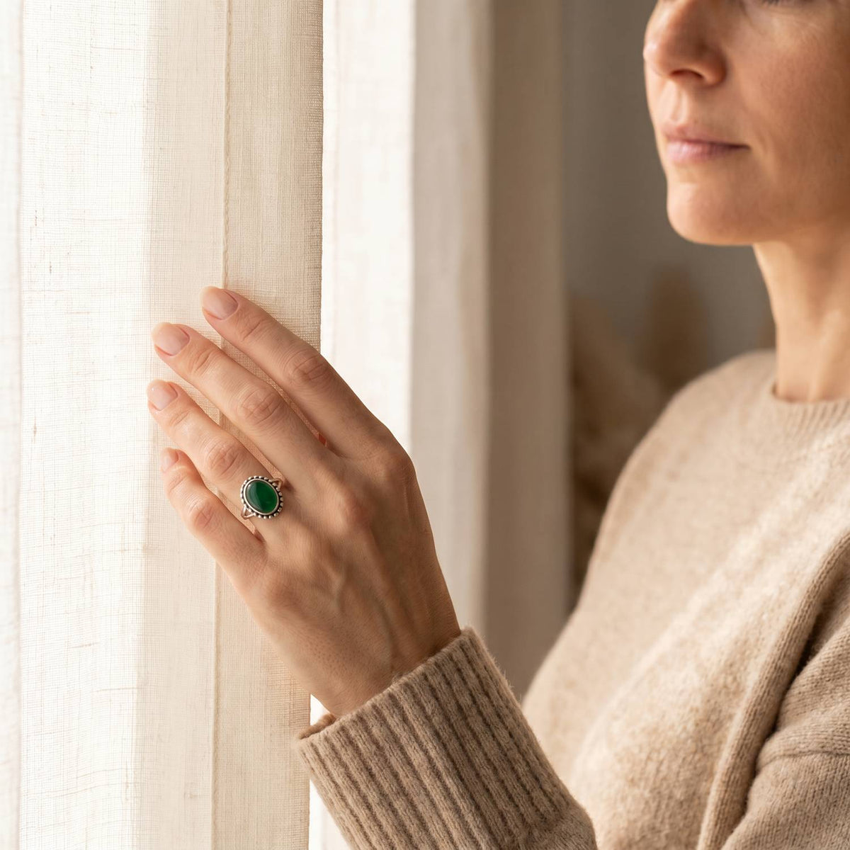 Frau trägt einen grüner Onyxring aus Silber am Fenster