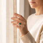 [KI] Frau trägt einen grüner Onyxring aus Silber am Fenster