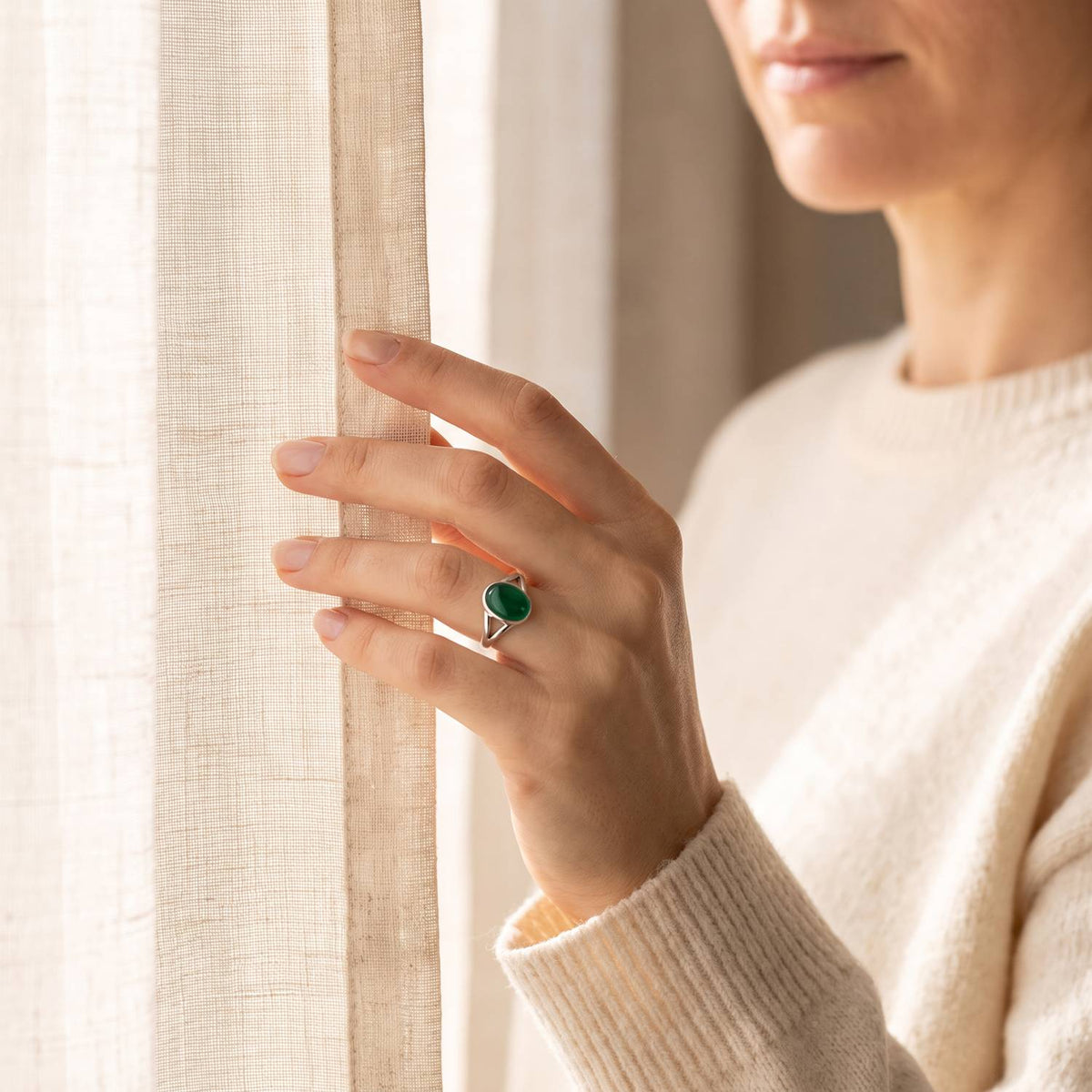 Frau trägt einen grüner Onyxring aus Silber am Fenster