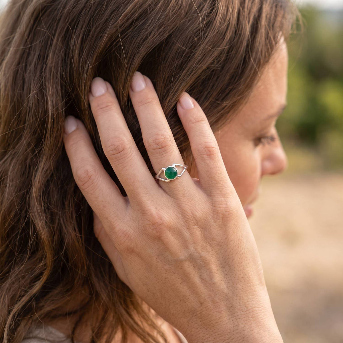 Frau trägt Silberring mit grüner Onyx an der Hand am Haar